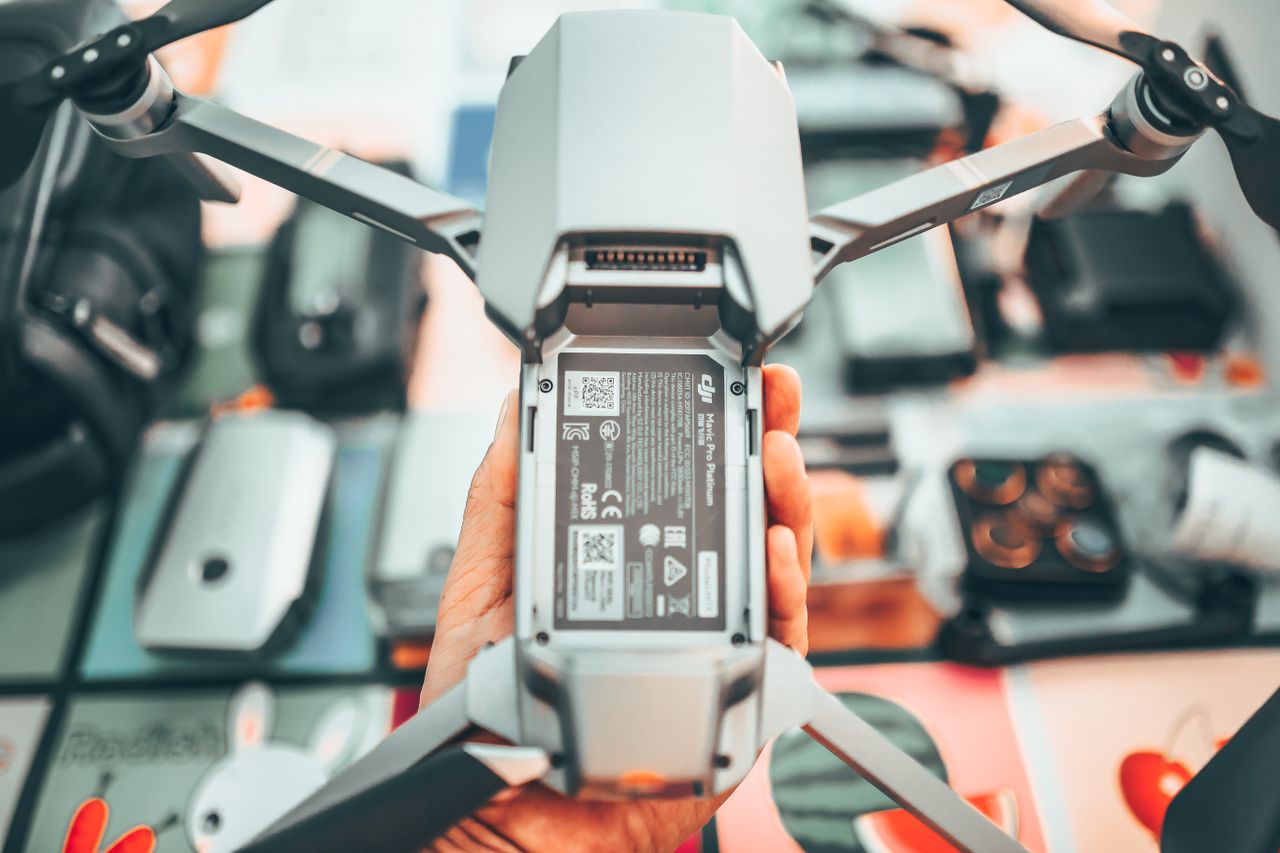 Top view of crop anonymous camera man showing drone with propellers at home in soft daylight